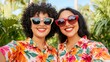 © medalinebow - Two Women Smiling Together in Colorful Floral Shirts Surrounded by Tropical Plants