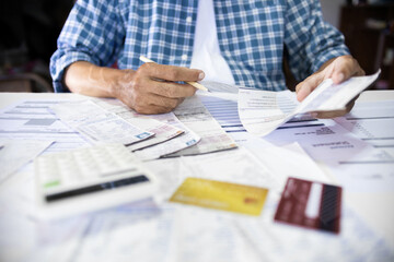 Asian man sitting at desk he holding receipt of expenses worry about find money to pay credit card debt and all loan bills. financial problem and inflation economy concept