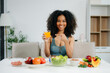 © Nuttapong punna - Smiling woman in a modern kitchen with fresh fruits, vegetables, blender, and orange juice, promoting clean eating, wellness