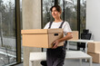 © zinkevych - Smiling female dark-haired young packaging service worker holding a big parcel