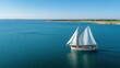 © Niken - A classic sailboat sailing on the deep blue sea, seen from above. The boat is wooden with white sails and has an elegant form. A clear sky overhead adds to its timeless charm.