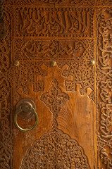 Wall Mural - New carved wooden door with metal decorative handle and arabic inscription closeup in Uzbekistan, Asia