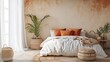 © Trident - Minimalist bedroom features a white bed with orange terracotta pillows and a woven rug near a palm tree with pouf seat furniture on a beige concrete wall.