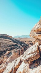 Wall Mural - Rocky Landscape Under Clear Blue Sky with Sunlit Hills in Distance