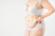 © staras - Tummy tuck, flabby skin with stretch marks on a fat belly, plastic surgery concept on light gray background