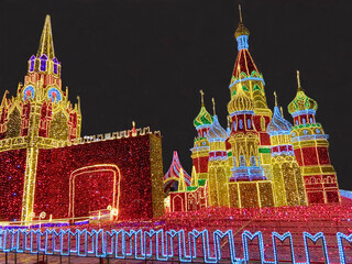 View of the illumination of the Spasskaya Tower, the Kremlin Wall and St. Basil's Cathedral from red yellow and blue lights at night. Sights of Moscow, World tourism.