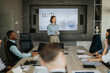 © qunica.com - A diverse group of business people engaged in a meeting with a presentation displayed on a screen. The setting emphasizes collaboration and teamwork in a modern office environment.