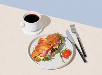 Wall Mural - Croissant sandwich with ham, cheese, tomato  and arugula on a plate on a light background