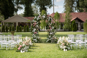 Wall Mural - Wedding ceremony. Very beautiful and stylish wedding arch, decorated with various fresh flowers, standing in the garden.