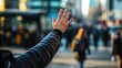 © sadewotito - A person's hand outstretched in a busy city street, blurred background.