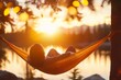 © Thanyarat - A person setting up a hammock between two trees, preparing for a relaxing weekend nap in nature