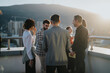 © qunica.com - A diverse group of business colleagues engage in a brainstorming session on a high tower balcony at sunset, fostering multicultural collaboration and teamwork in a dynamic urban setting.