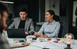 © qunica.com - A group of people engaged in brainstorming and analysis during a late-night office meeting. They are collaborating on projects and strategizing to meet tight deadlines in a modern workspace.