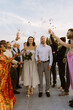 © Maskot - Group of male and female friends throwing confetti on newlywed couple