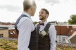 © Maskot - Loving gay couple looking at each other while standing on rooftop