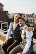 © Maskot - Portrait of smiling married gay couple sitting together on rooftop