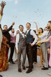 © Maskot - Happy gay couple having fun with guests during wedding ceremony on rooftop