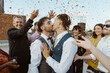 © Maskot - Loving gay couple kissing and guests throwing confetti during ceremony