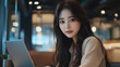 © Daniil - Young Korean woman working on a laptop in a modern cafe setting during the day