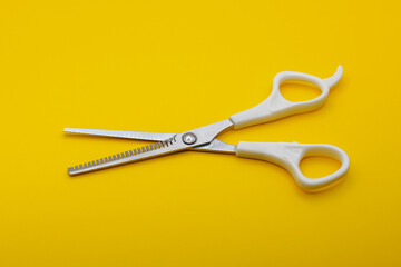 Top and side views of a pair of multi-purpose scissors with white handles isolated on a yellow background. A complement to everyday essentials.