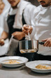 © Maskot - Male chef holding saucepan while garnishing food in kitchen at restaurant