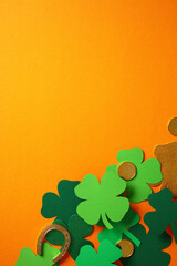 Wall Mural - St. Patrick's Day flat lay composition with green four leaf clover, gold coins, and a horseshoe on an orange background.