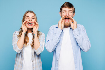 Wall Mural - Young couple two friend family man woman wear shirt casual clothes together scream sharing hot news about sales discount with hands near mouth isolated on plain blue cyan background Lifestyle concept