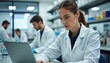 © umut hasanoglu - Scientist uses laptop in a busy laboratory setting, collaborating with colleagues on research.