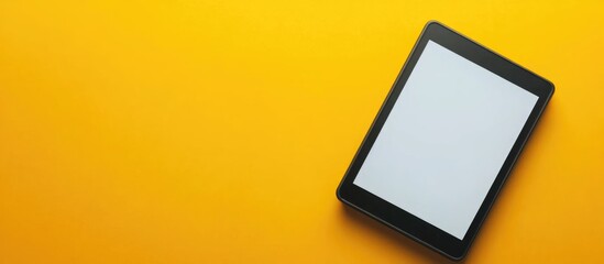 Digital tablet with blank screen on a vibrant yellow background with ample copy space.