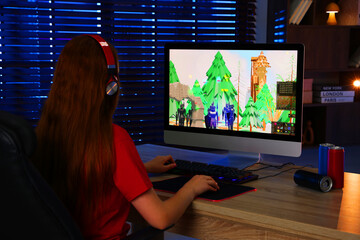 Wall Mural - Girl playing video game with keyboard and mouse at table in dark room