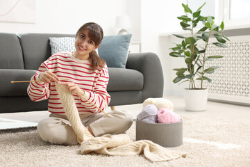 Wall Mural - Beautiful woman knitting with needles on floor at home