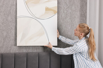 Wall Mural - Female decorator hanging abstract picture in room