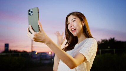 Wall Mural - Woman Enjoys Joyful Evening Selfie with Smartphone at Sunset in Vibrant Outdoor City, Capturing Excitement and Happiness in Moment. Asian Digital technology lifestyle