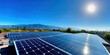 © javu - Solar panels on rooftop under bright sunlight with mountains in background