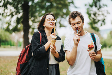 Poster - Two multicultural students relax and enjoy ice cream while spending time together in a park during their break from classes, reflecting happiness and friendship.