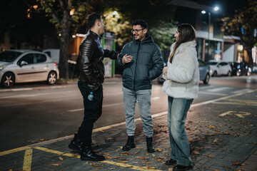 Sticker - A group of friends engaged in a casual, cheerful conversation outdoors in an urban area at night, showcasing friendship and leisure in a lively, modern city setting.