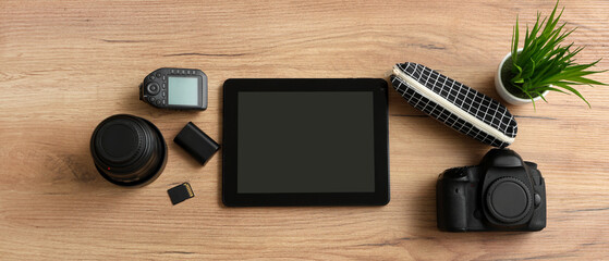 Wall Mural - composition with tablet computer and professional photographer's equipment on wooden background