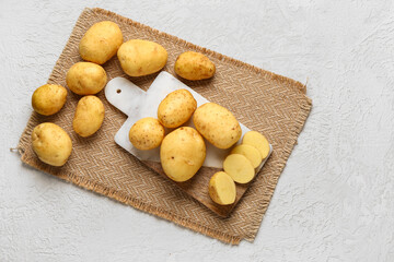 Sticker - Board with raw baby potatoes and slices on white background