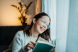 © Dusan - Young caucasian woman reading book or learning by the window
