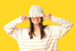 © Pixel-Shot - Beautiful young woman in stylish knitted hat on yellow background