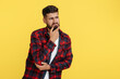 © Screaghin - Confused bearded hipster young man in plaid shirt thinking over yellow background