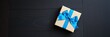 © Michael - Decorative gift box with blue ribbon on black wooden surface for celebrations and special occasions