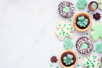 Aufkleber - St Patricks Day dessert side border over a white stone background. Shamrock and green cookies, tarts, chocolate and candy. Above view. Copy space.