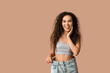 © Pixel-Shot - Surprised young African-American woman in loose jeans on beige background. Weight loss concept