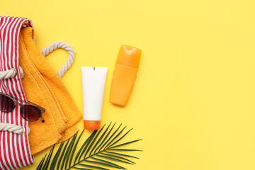 Wall Mural - Composition with bottles of sunscreen cream, palm leaf, bag and sunglasses on yellow background