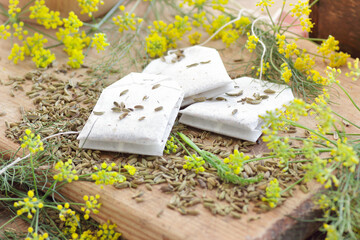 Wall Mural - Fennel seed tea bags on wooden kitchen background with fresh flowers nearby, copy space, natural medicine, drink for breast milk production, sleep and stress care concept