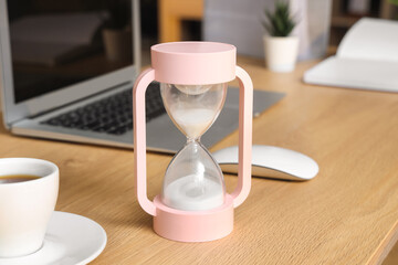 Wall Mural - Pink hourglass on table in office, closeup