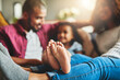 © peopleimages.com - Feet, family and bonding in living room, home and parents with child, group and comfortable in socks. House, relax and people in lounge with kid, mom and dad with youth on couch, legs and chilling
