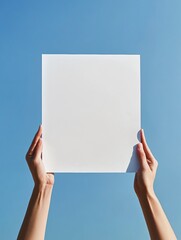 Aufkleber - Hands holding a blank white sheet against a clear blue sky during daylight hours with no visible clouds. Generative AI