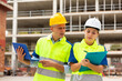 © JackF - Two architects in reflective waistcoats with laptop and papers discussing construction plan at building site